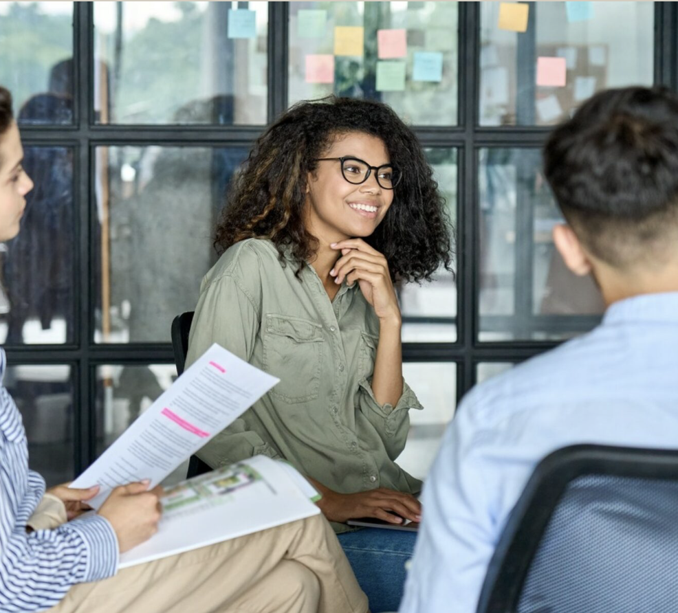 A young person in a mentoring session with support workers, smiling as they discuss plans together.